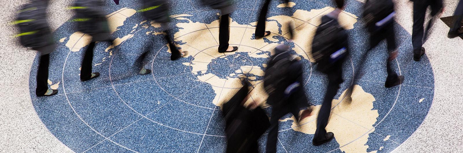 Business leaders walking across globe marble flooring